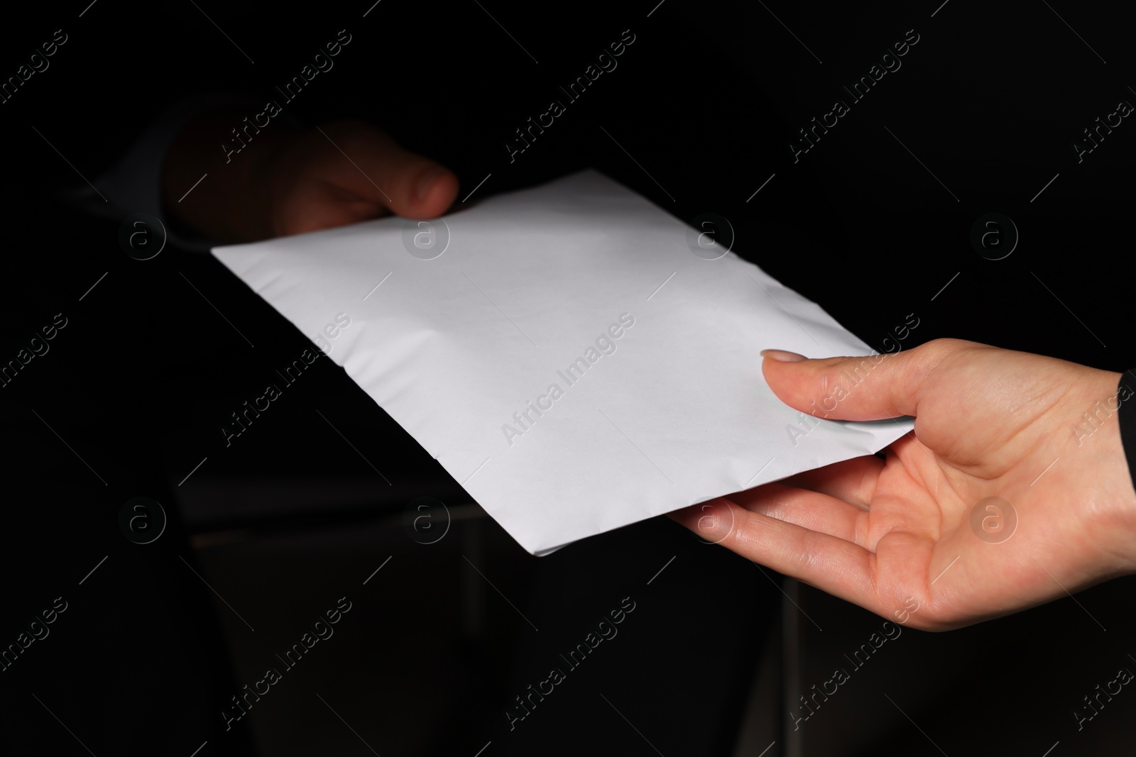 Photo of Corruption concept. Woman giving envelope with money to man on black background, closeup