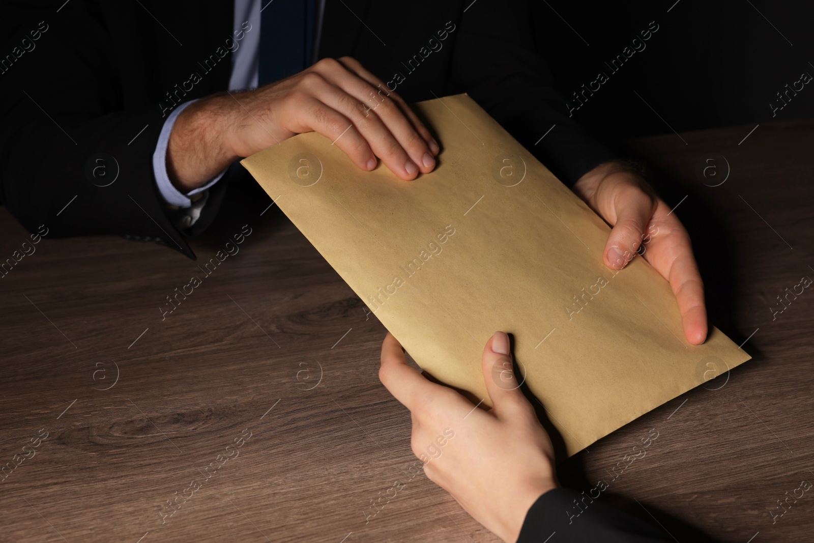 Photo of Corruption concept. Woman giving envelope with money to man at wooden table, closeup