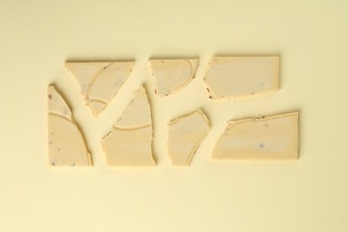 Photo of Pieces of tasty white chocolate on beige background, top view