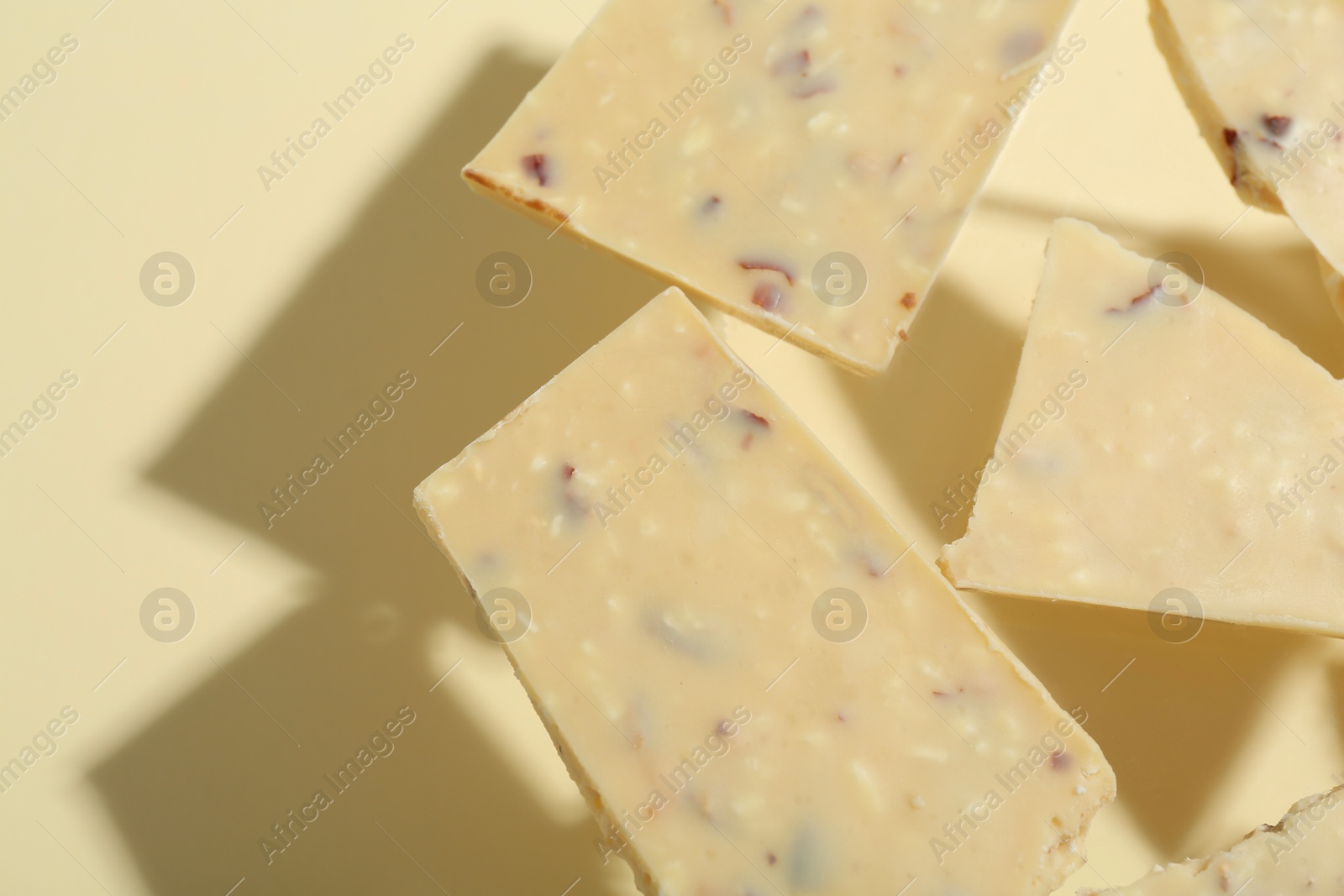 Photo of Pieces of tasty white chocolate on beige background, top view