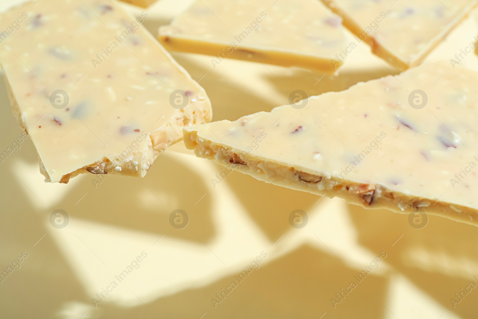 Photo of Pieces of tasty white chocolate on beige background, closeup