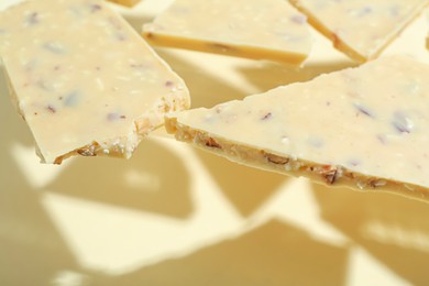 Photo of Pieces of tasty white chocolate on beige background, closeup