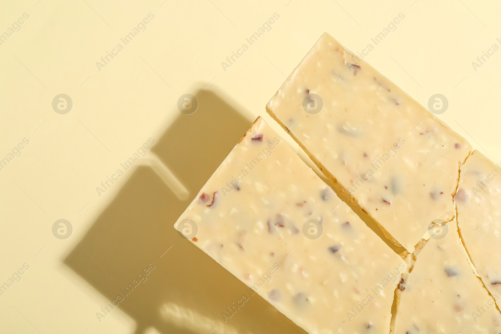 Photo of Pieces of tasty white chocolate on beige background, top view. Space for text