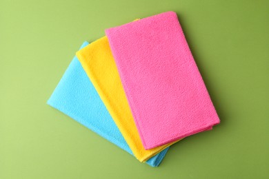 Photo of Different microfiber cloths on green background, top view