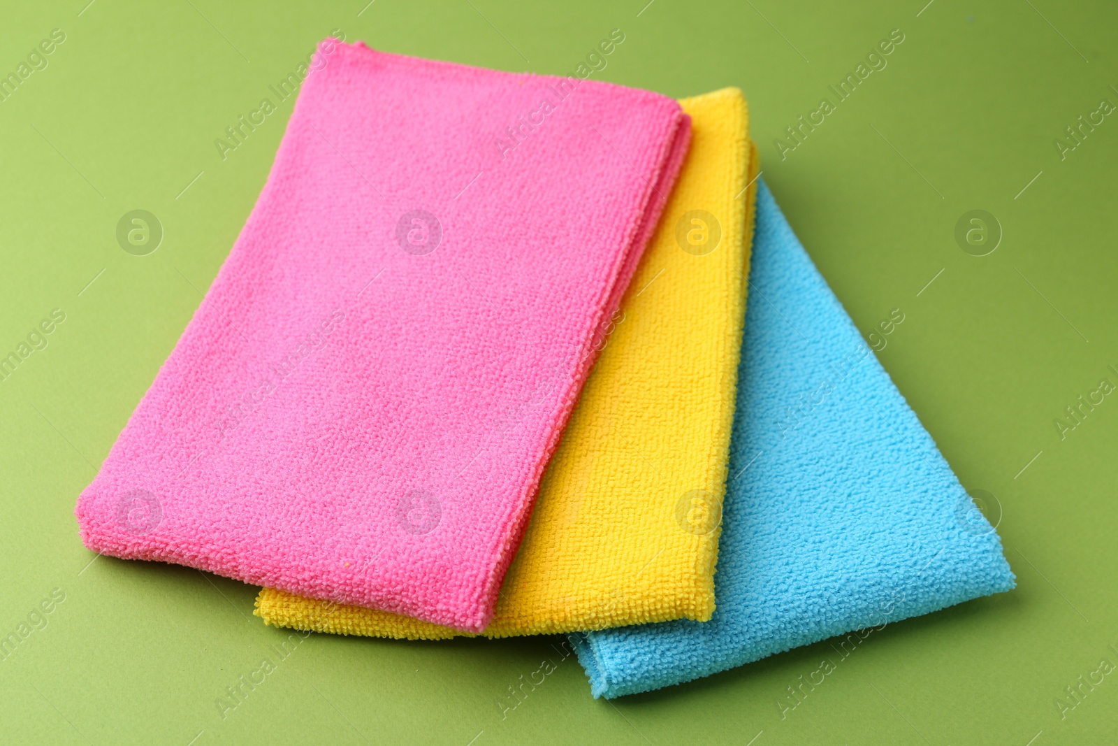 Photo of Different microfiber cloths on green background, closeup