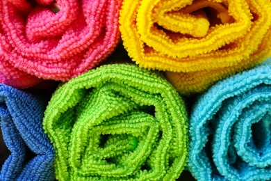 Photo of Rolled different microfiber cloths as background, closeup