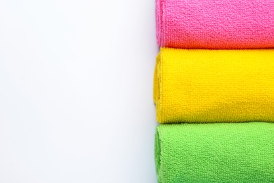 Photo of Rolled different microfiber cloths on white background, top view. Space for text