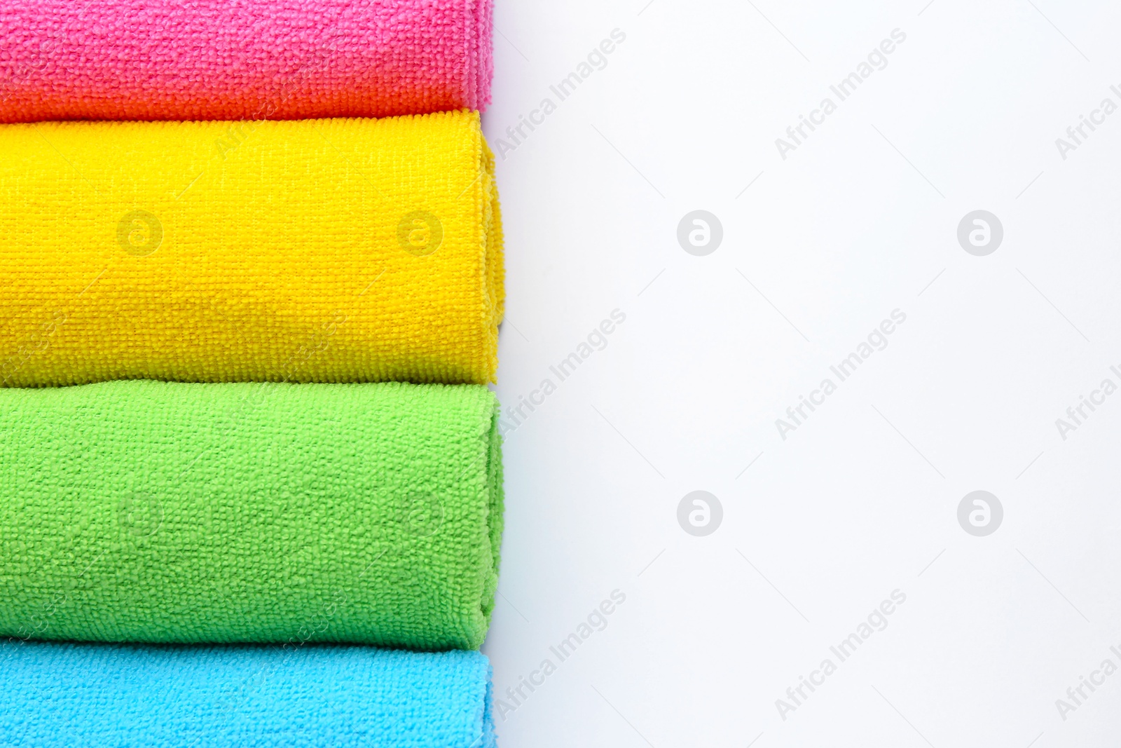 Photo of Rolled different microfiber cloths on white background, top view. Space for text