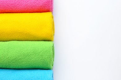 Photo of Rolled different microfiber cloths on white background, top view. Space for text