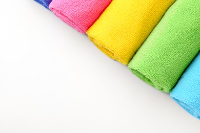 Photo of Rolled different microfiber cloths on white background, top view. Space for text