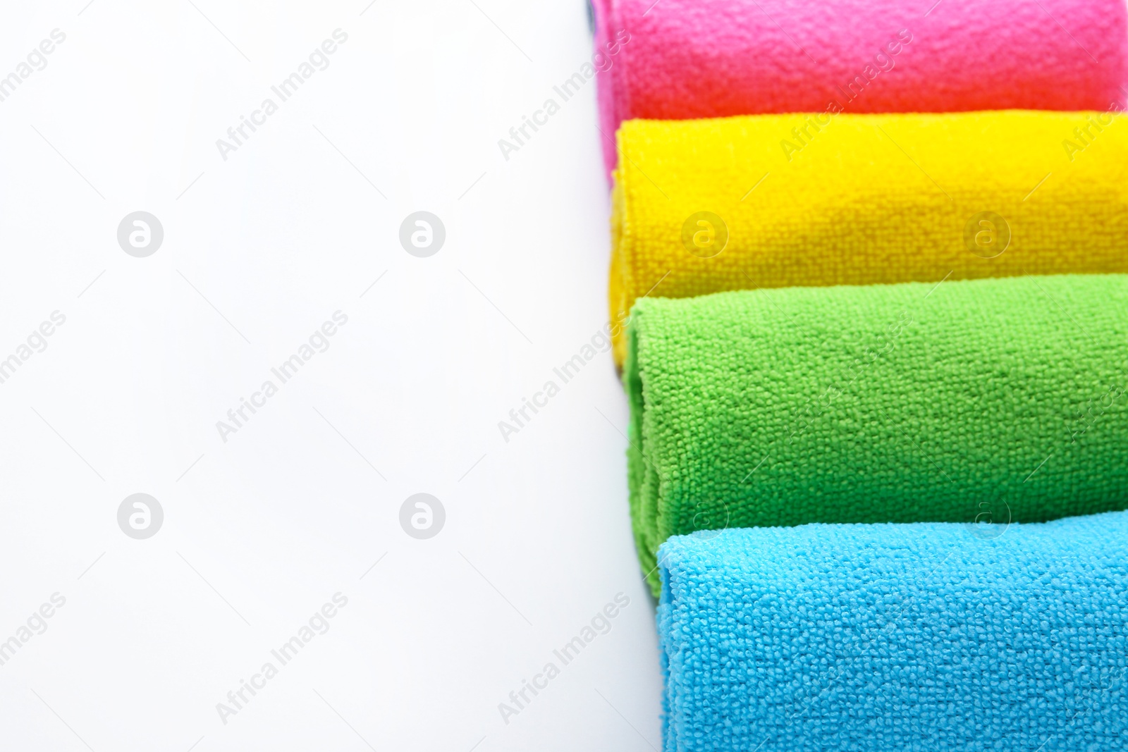 Photo of Rolled different microfiber cloths on white background, closeup. Space for text