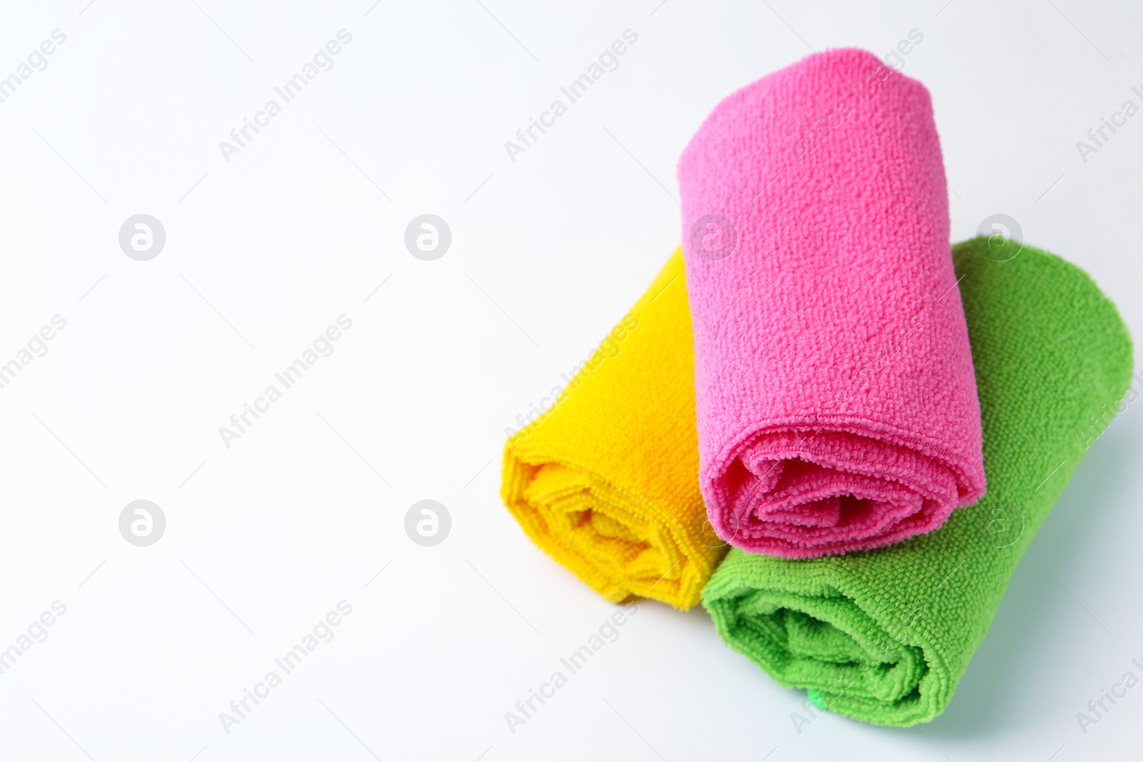 Photo of Rolled different microfiber cloths on white background, space for text