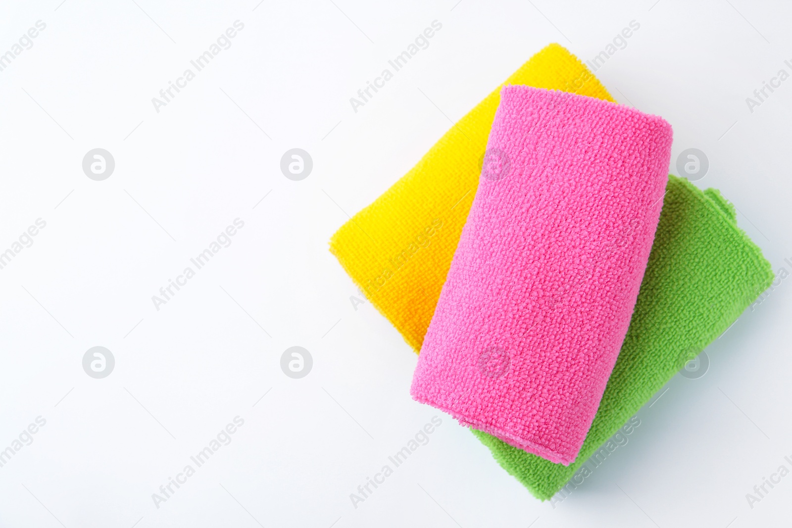 Photo of Rolled different microfiber cloths on white background, top view. Space for text