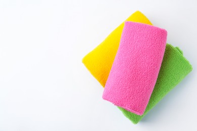 Photo of Rolled different microfiber cloths on white background, top view. Space for text