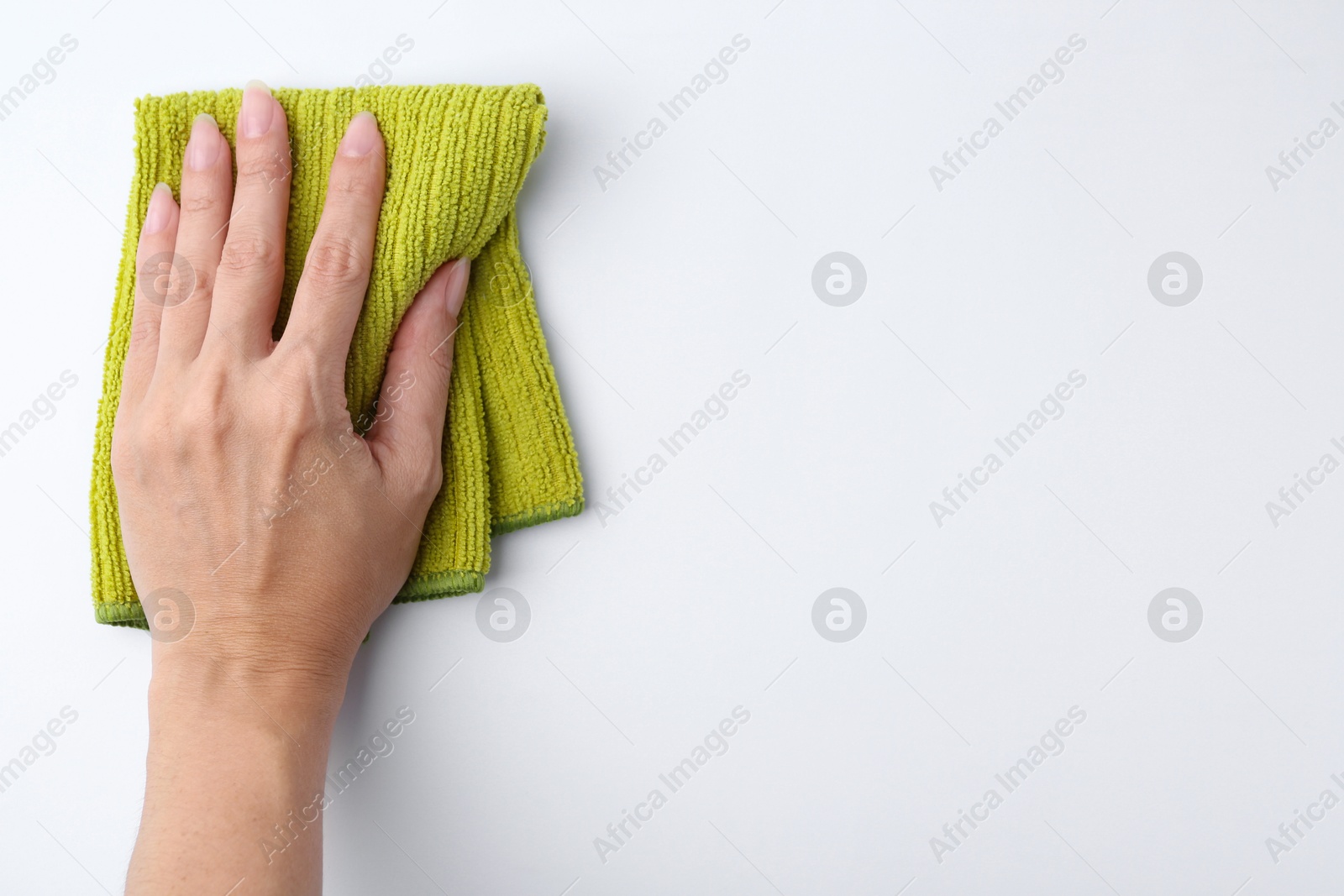 Photo of Woman with clean green microfiber cloth on white background, top view. Space for text