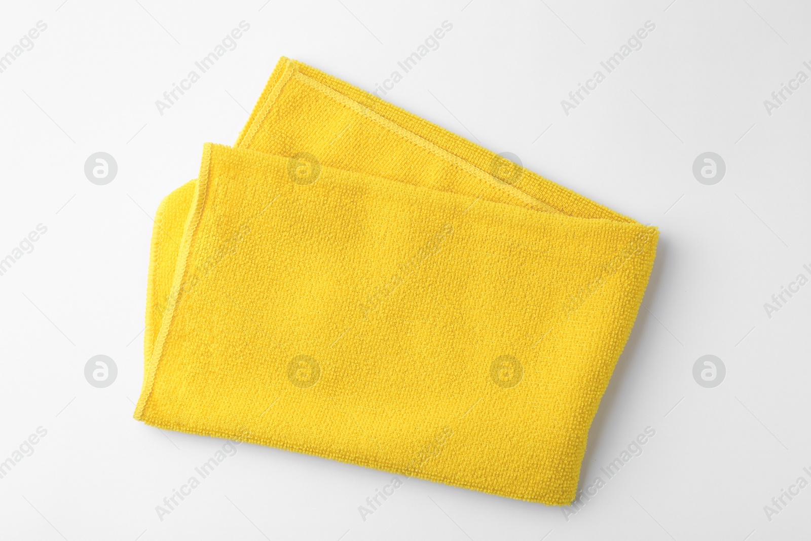 Photo of Clean yellow microfiber cloth on white background, top view