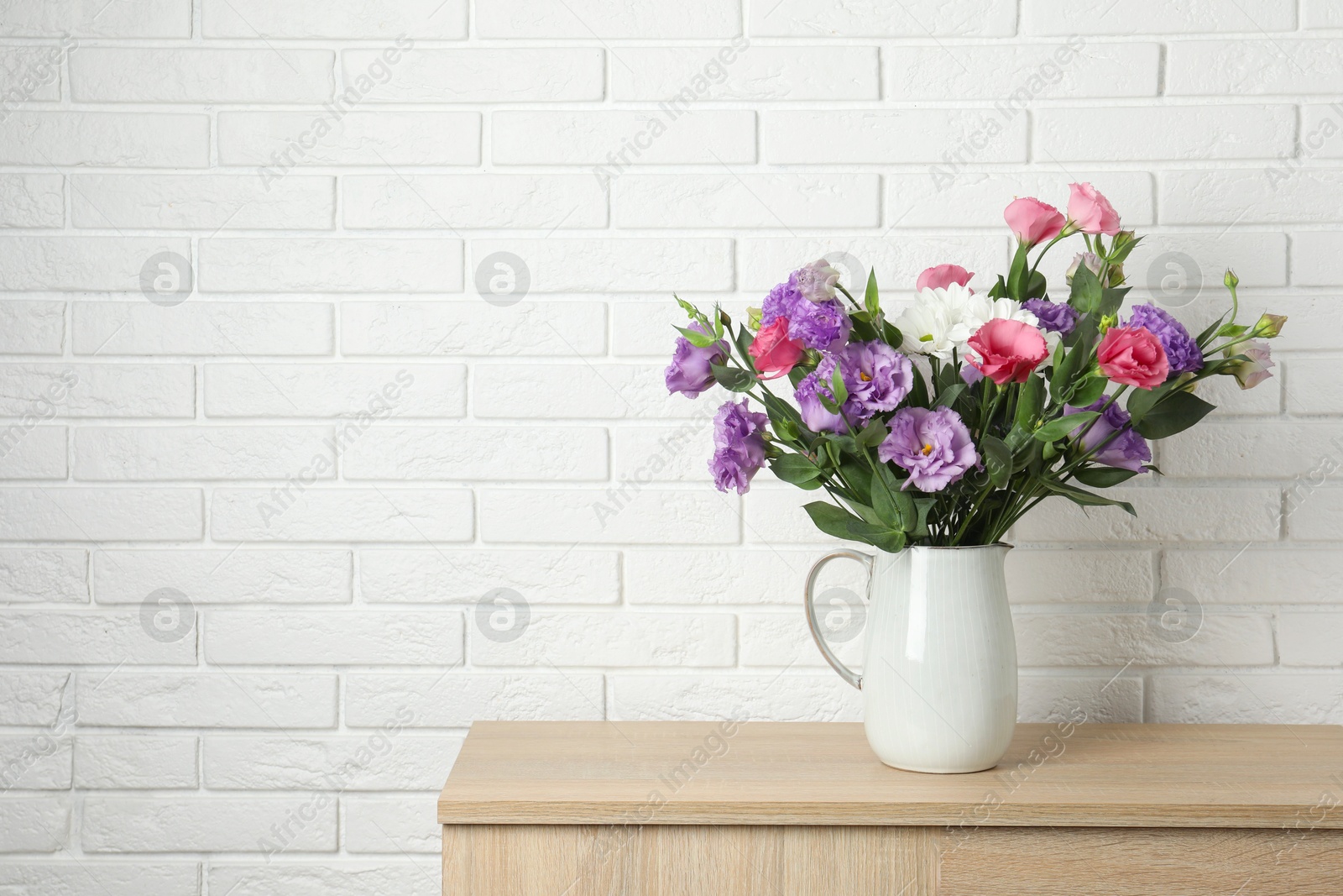 Photo of Vase with beautiful eustoma flowers on wooden chest of drawers, space for text