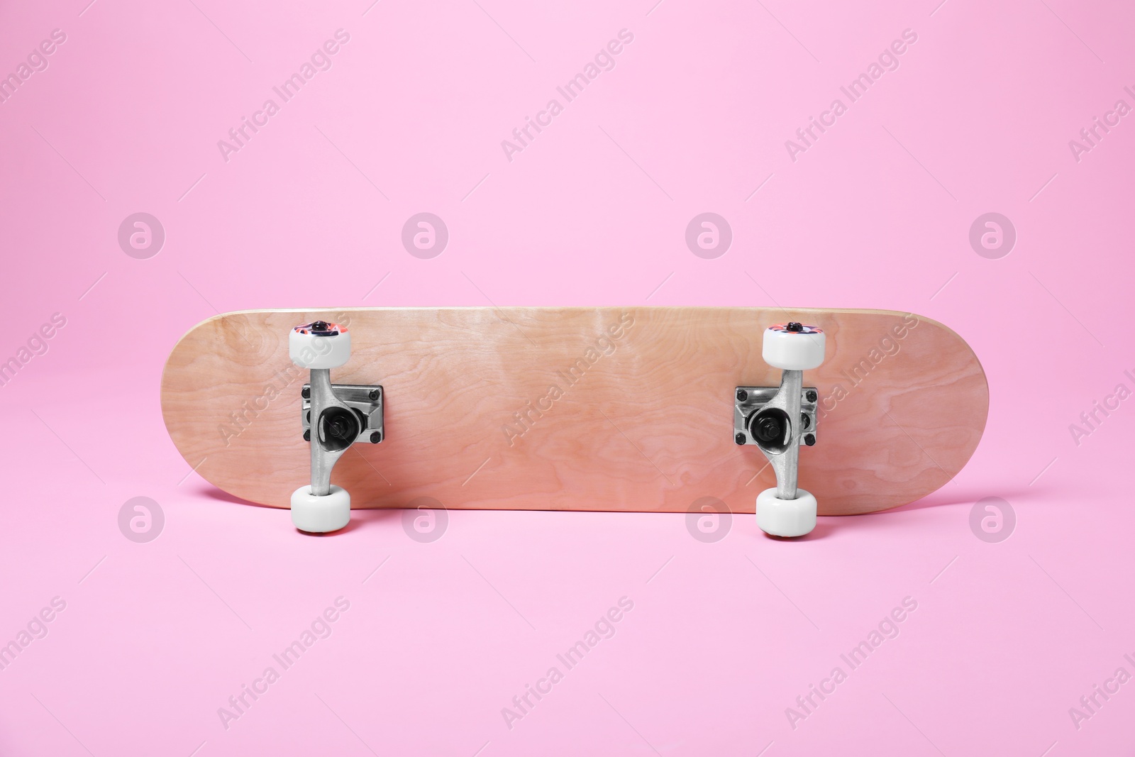 Photo of One skateboard on pink background. Sports equipment