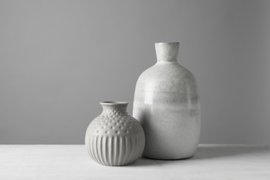 Photo of Two stylish vases on white table against grey background