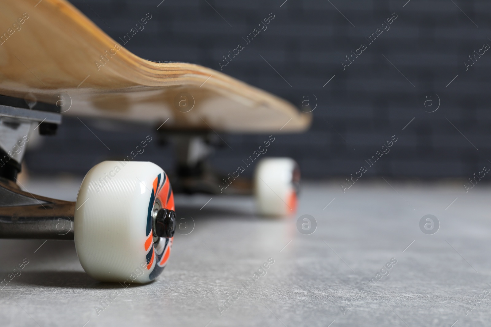 Photo of One modern skateboard on grey surface, closeup. Space for text