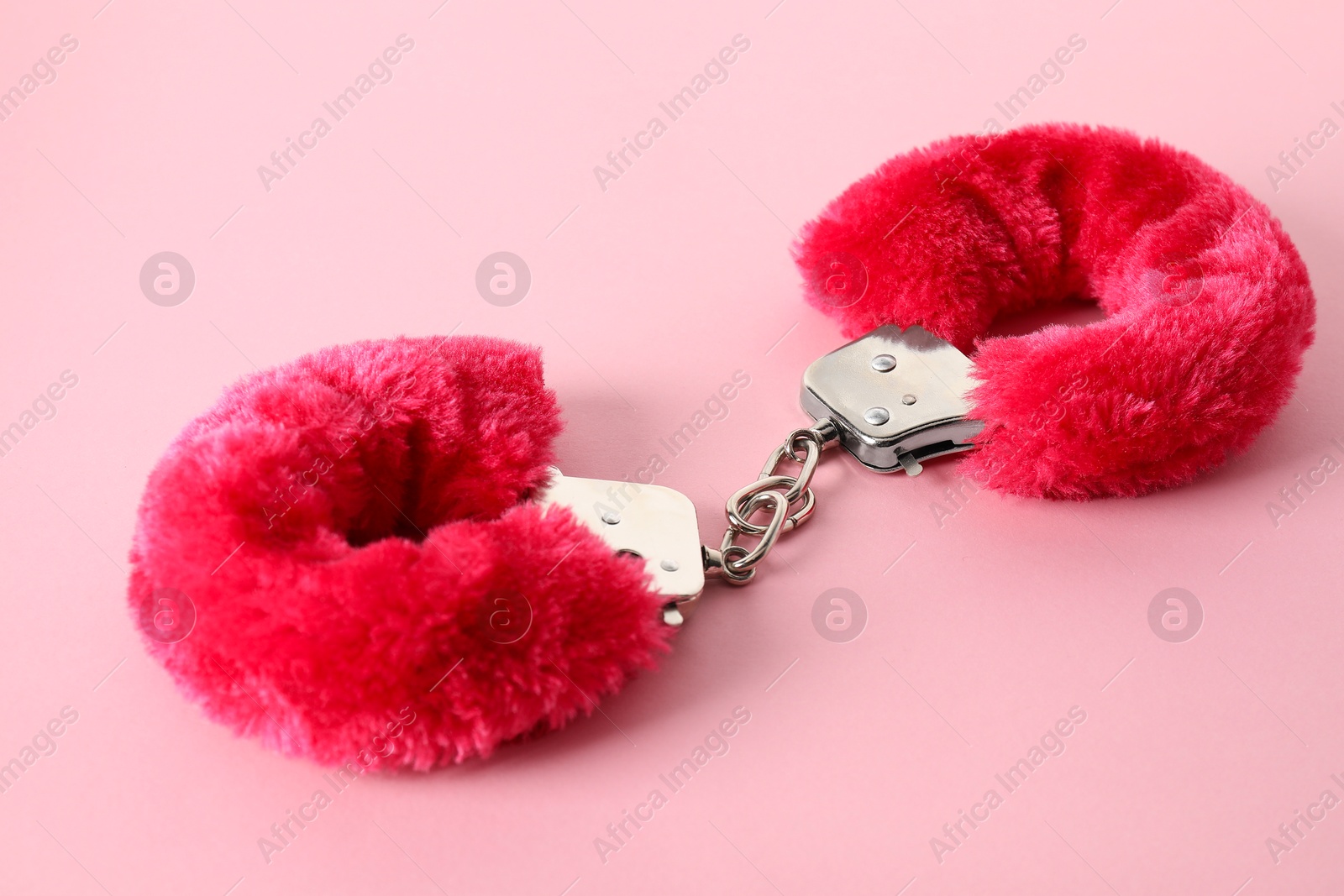 Photo of Fluffy handcuffs on pink background, closeup. Sex toy