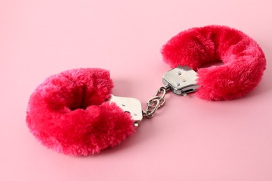 Photo of Fluffy handcuffs on pink background, closeup. Sex toy