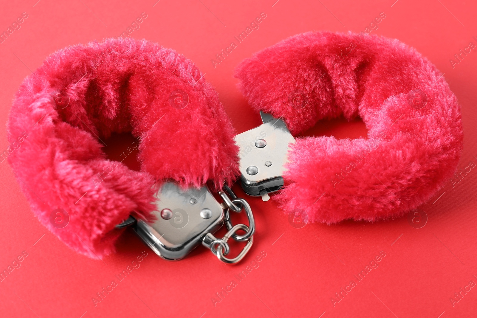 Photo of Pink fluffy handcuffs on color background, closeup. Sex toy