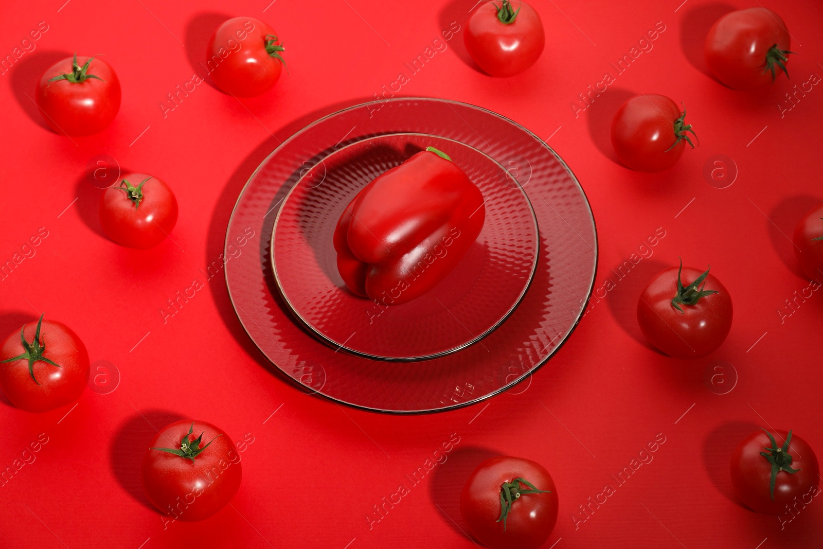 Photo of Plate with bell pepper and tomatoes on red background