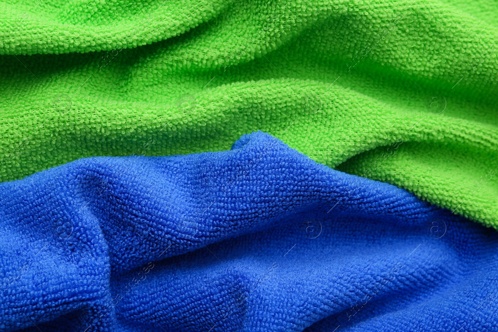 Photo of Clean green and blue microfiber cloths as background, closeup