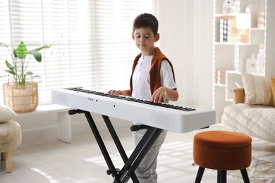 Photo of Cute boy playing synthesizer at home. Electronic musical instrument