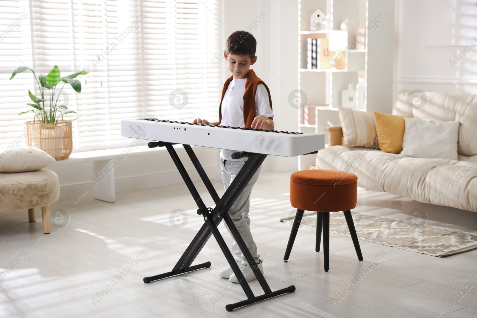 Photo of Cute boy playing synthesizer at home. Electronic musical instrument