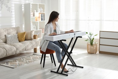 Photo of Woman playing synthesizer at home. Electronic musical instrument