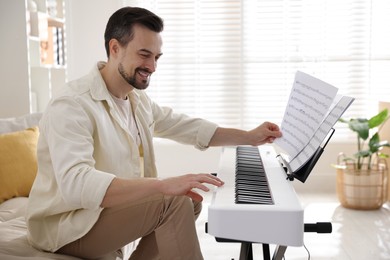 Photo of Smiling man playing synthesizer at home. Electronic musical instrument