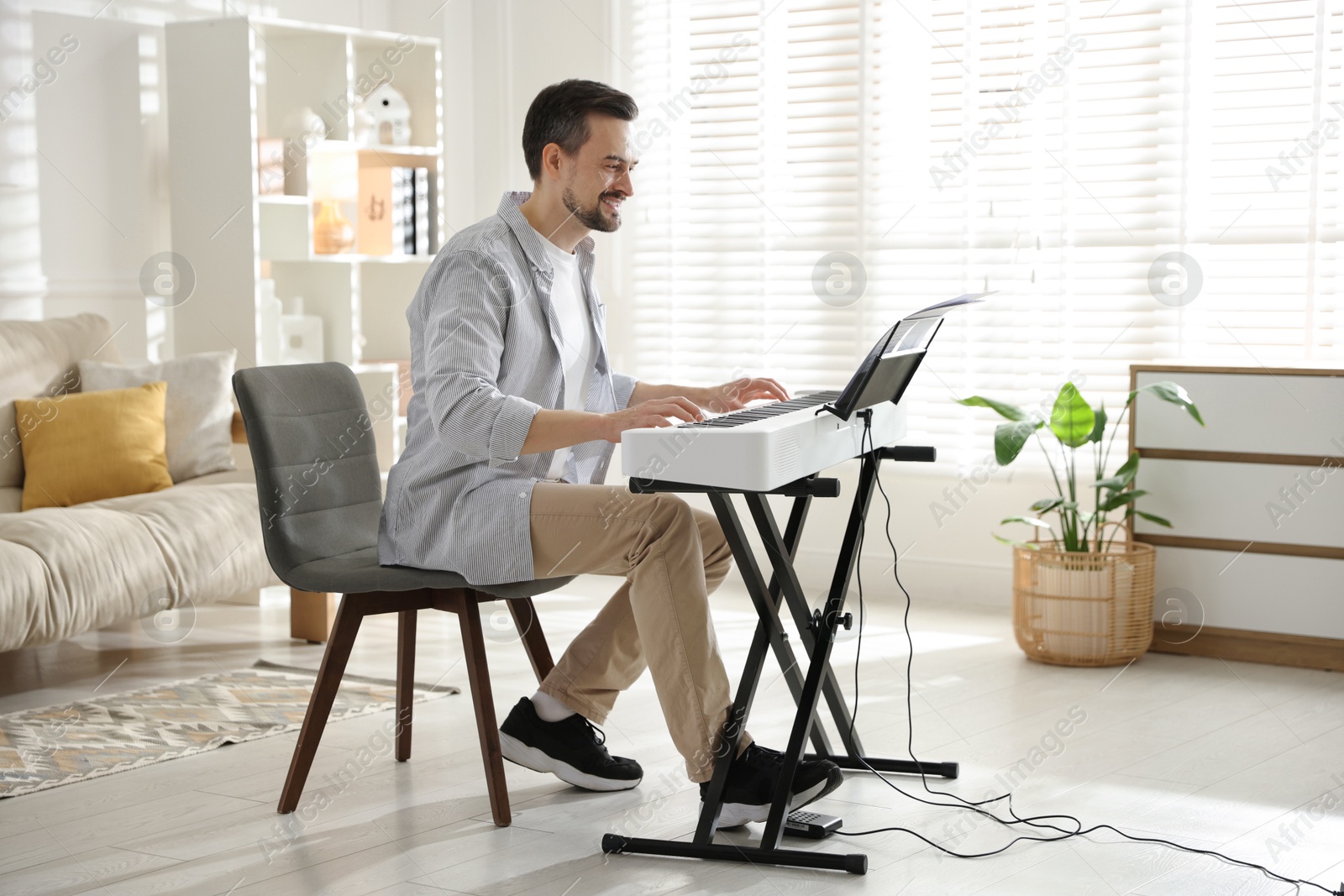 Photo of Smiling man playing synthesizer at home. Electronic musical instrument