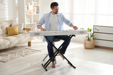 Photo of Smiling man playing synthesizer at home. Electronic musical instrument