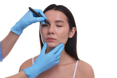 Photo of Doctor drawing marks on patient's nose for plastic surgery operation against white background, closeup