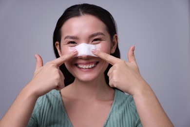 Photo of Woman with medical bandage on her nose after plastic surgery operation against light grey background