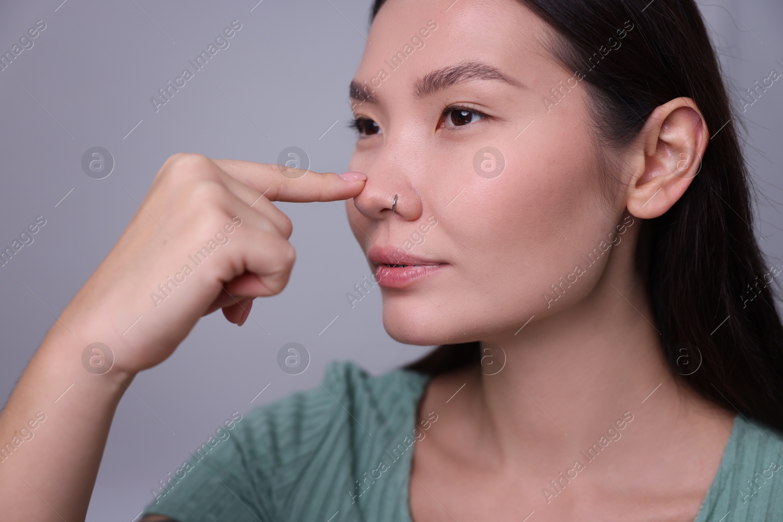 Photo of Woman touching her nose on light grey background, closeup