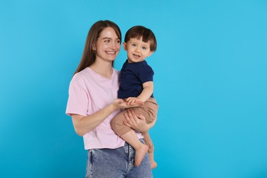 Photo of Happy mother with her cute little son on light blue background, space for text