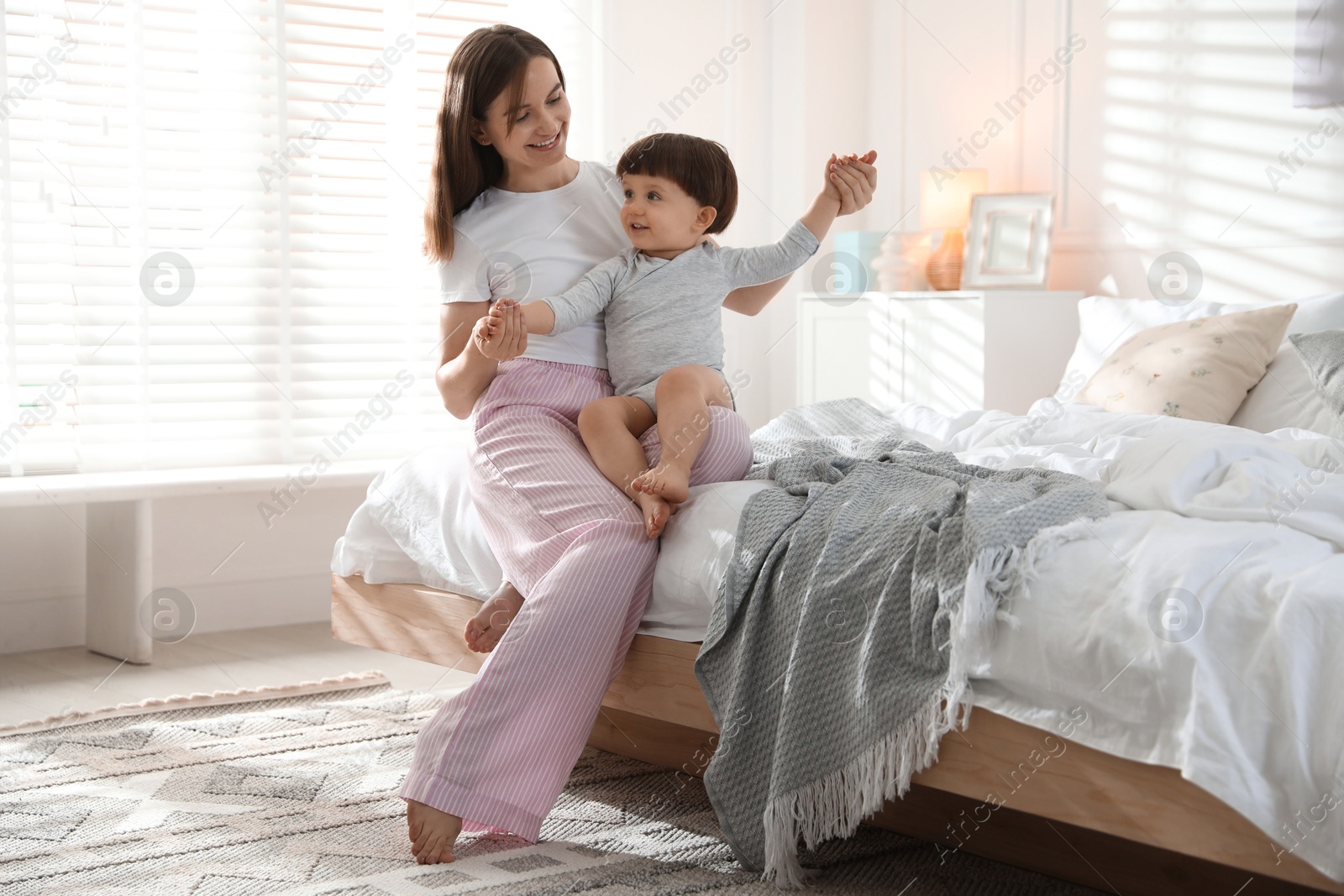 Photo of Happy mother playing with her little son in bedroom