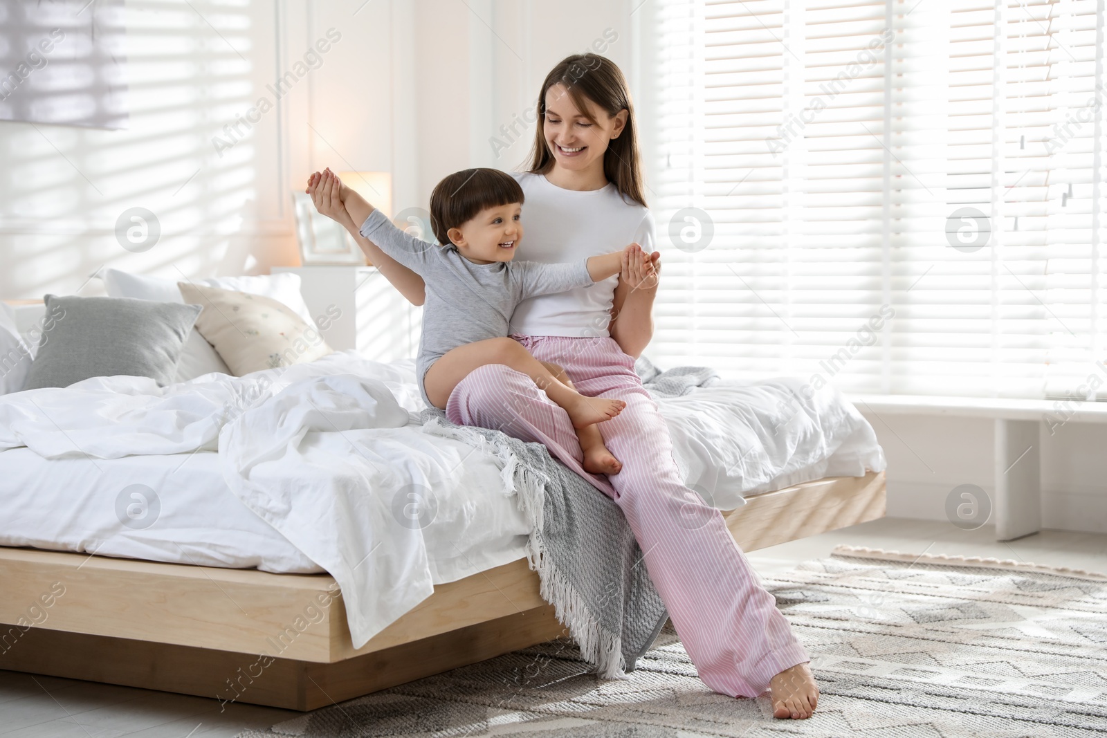 Photo of Happy mother playing with her little son in bedroom