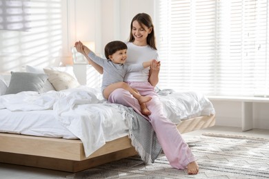 Photo of Happy mother playing with her little son in bedroom