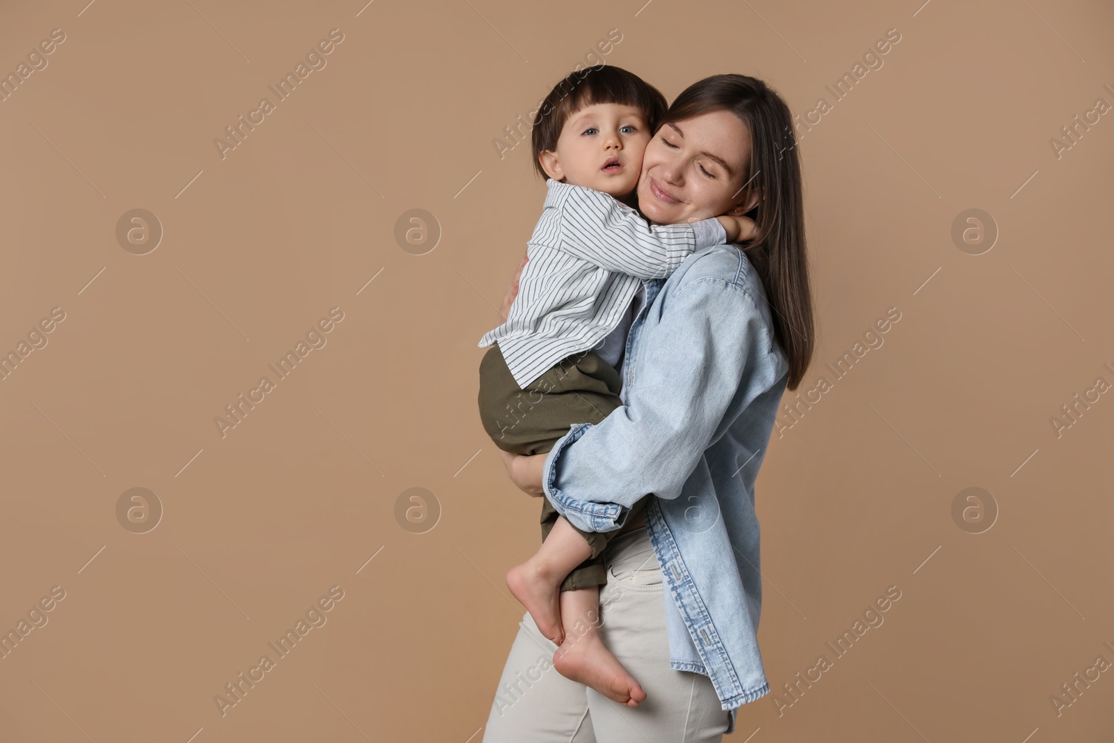 Photo of Family portrait of mother hugging her little son on beige background. Space for text