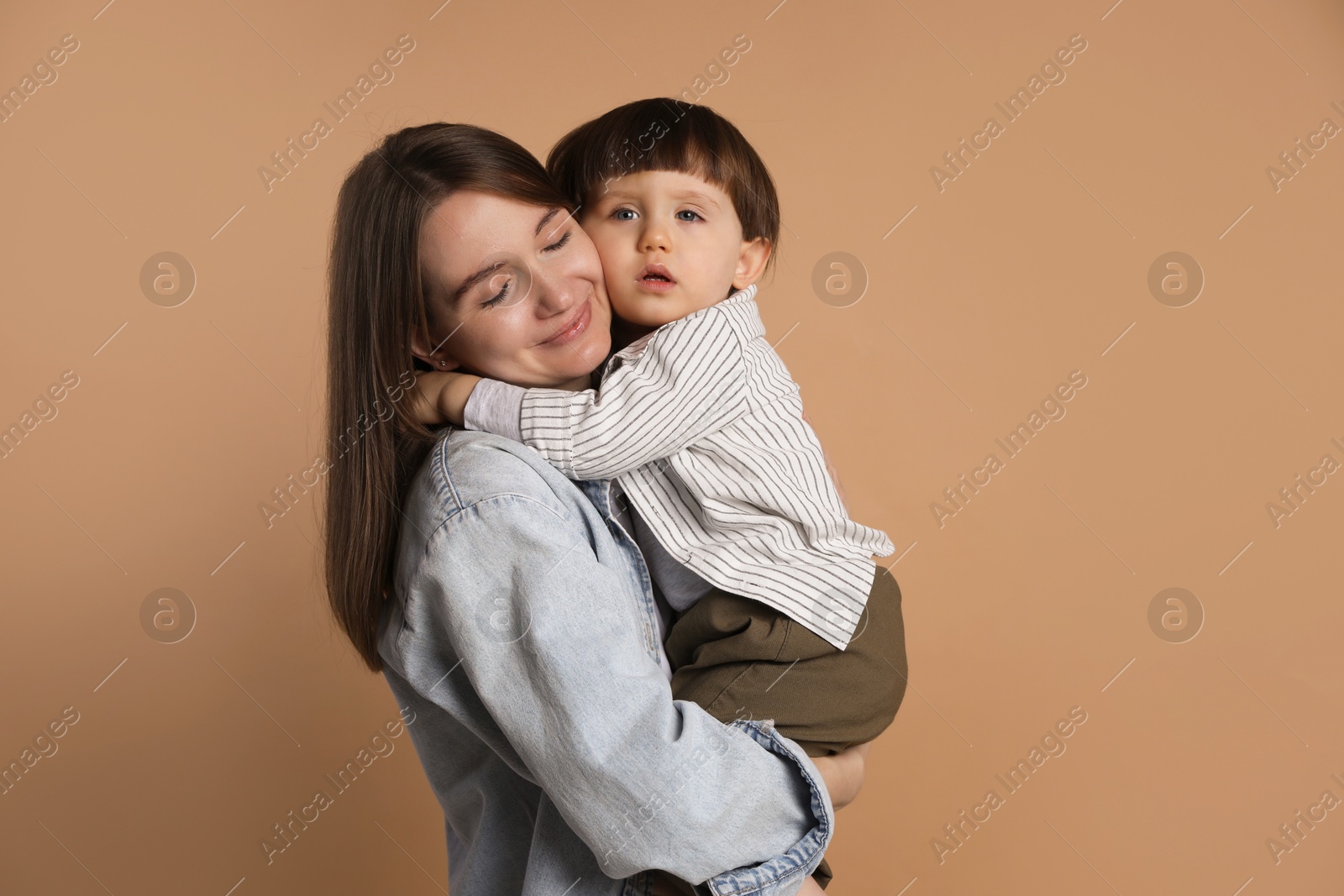 Photo of Family portrait of mother hugging her little son on beige background