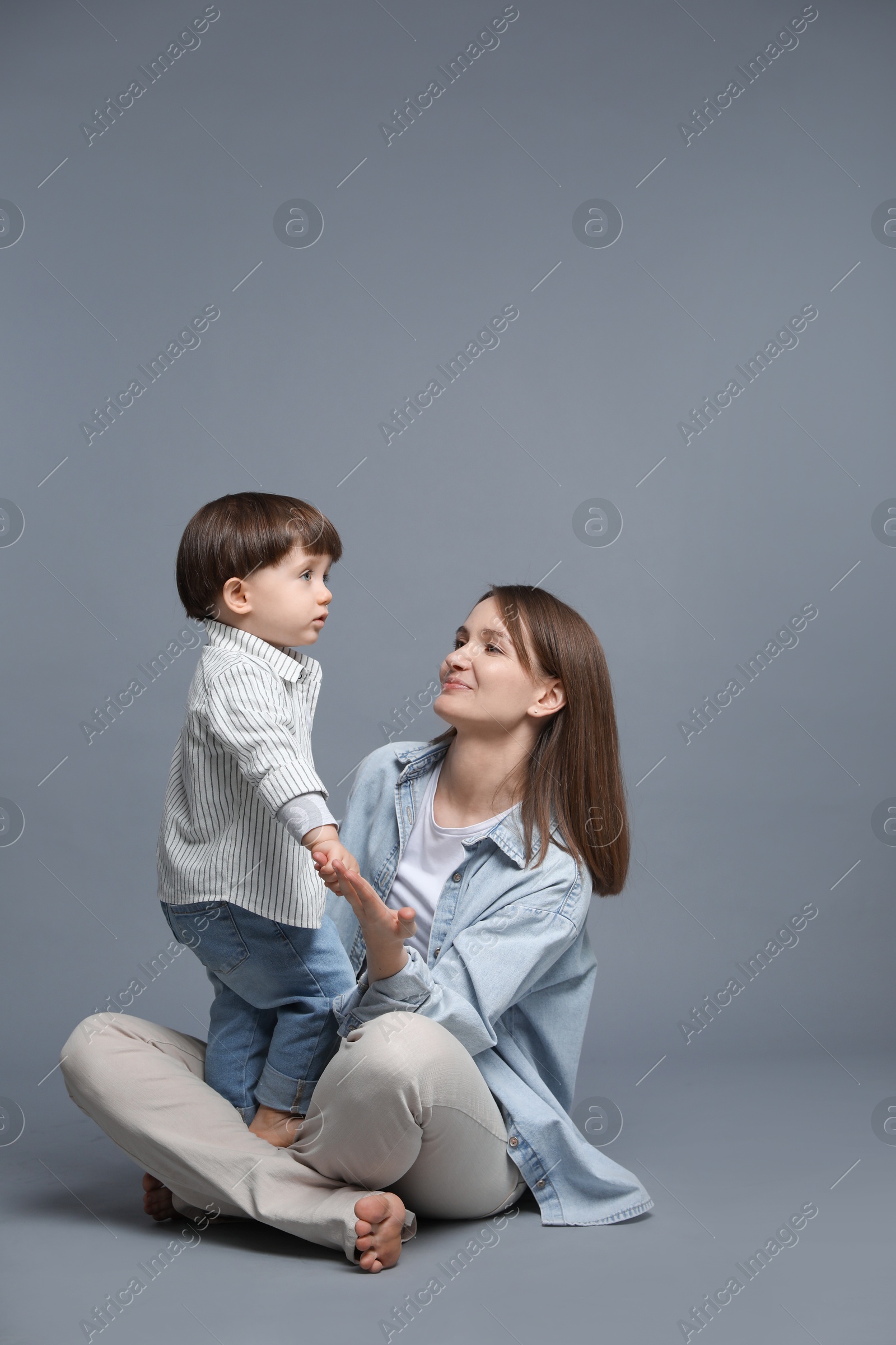 Photo of Mother with her little son on grey background. Space for text