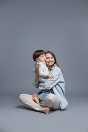 Photo of Happy mother hugging her little son on grey background