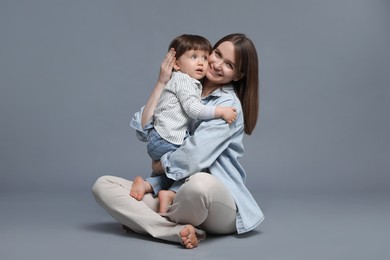 Photo of Happy mother hugging her little son on grey background