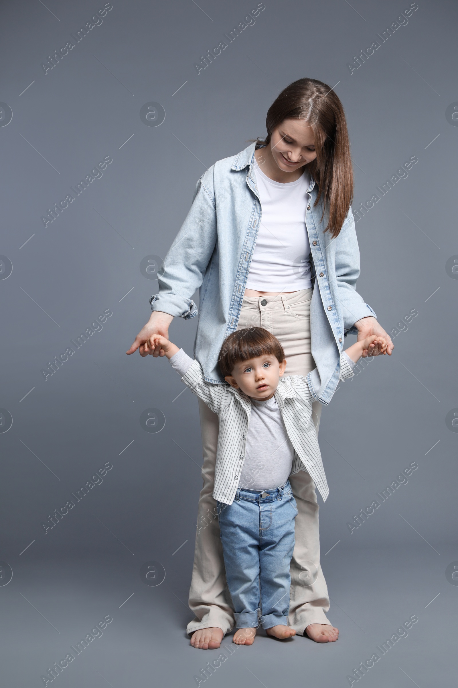 Photo of Happy mother with her little son on grey background