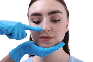 Doctor checking patient's nose before plastic surgery operation on white background, closeup