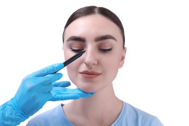 Photo of Doctor drawing marks on patient's nose for plastic surgery operation against white background, closeup